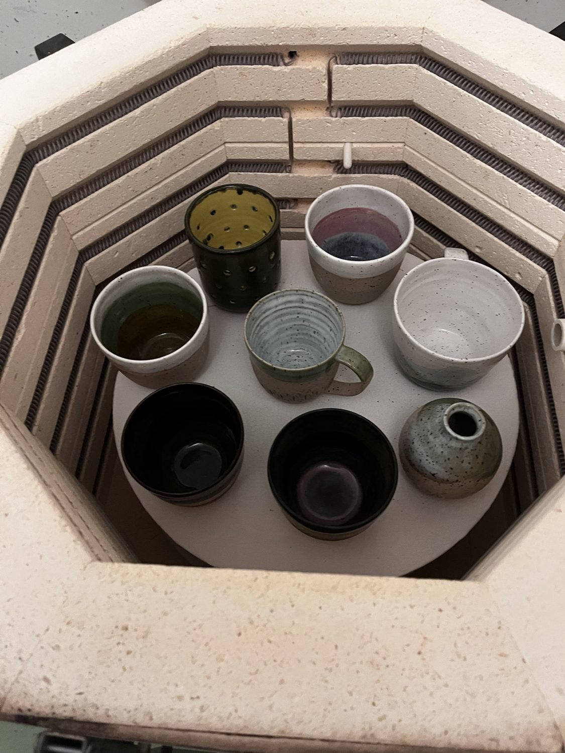 Blick in den Brennofen mit fertig gebrannten Bechern, Tassen und einer kleinen Vase